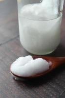 spoon with cold coconut oil on table photo