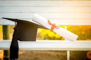 Graduation cap, Hat with degree paper on white wood table, abstract light background Empty ready for your product display or montage. photo