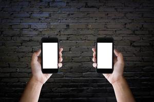 Man's hands holding blank screen of a smartphone at the old black brick wall. photo