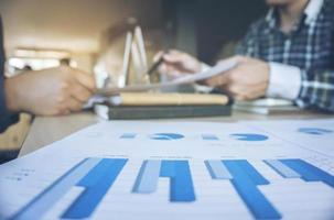 equipo de negocios dos colegas discutiendo el trabajo con muchos gráficos de documentos en una reunión de equipo hablando del concepto de comunicación de lluvia de ideas. foto