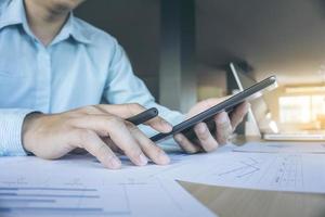 Closeup shot of business man's hands using tablet with many document graph and laptop in morning photo