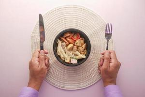 young man with fork waiting in from on a plate full of vegetable photo