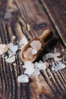 close up of pink rock salt in a wooden spoon on table photo
