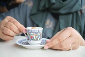 women holding a a cup of turkish coffee on table outdoor photo