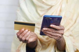 senior women hand holding credit card and using smart phone shopping online photo