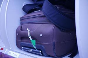 suitcase in a overhead baggage area in a Airplane cabin photo