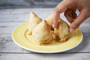 elige a mano una singara de comida india en un plato foto