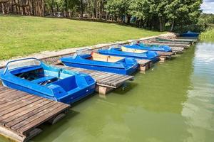 colored old vintage plastic catamarans and boats near a wooden pier on the shore of a large lake photo