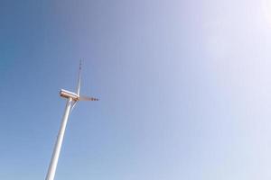 rotating blades of a windmill propeller on blue sky background. Wind power generation. Pure green energy. photo