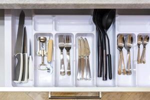 cutlery spoons forks knives and tea spoon on the shelf in the kitchen cupboard photo