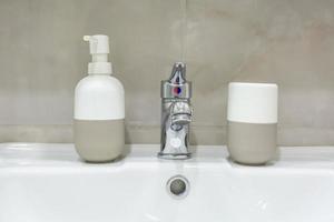 Soap and shampoo dispensers near Ceramic Water tap sink with faucet in expensive loft bathroom photo