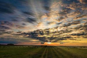 panorama of blue red sky background with evening fluffy curly rolling clouds with setting sun. Good windy weather photo