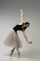 ballerina in a bodysuit and a white skirt improvises classical and modern choreography in a photo studio