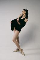 ballerina in a bodysuit and a black jacket improvises classical and modern choreography in a photo studio