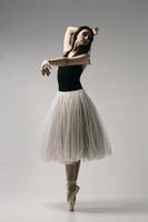 bailarina en traje de cuerpo y falda blanca improvisa coreografía clásica y moderna en un estudio fotográfico foto