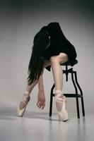 ballerina in a bodysuit and a black jacket improvises classical and modern choreography in a photo studio