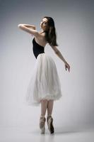 a ballerina in a bodysuit and a white skirt improvises classical and modern choreography in a photo studio