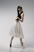 ballerina in a bodysuit and a white skirt improvises classical and modern choreography in a photo studio