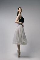 ballerina in a bodysuit and a white skirt improvises classical and modern choreography in a photo studio