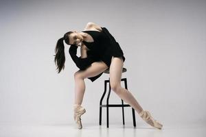 bailarina en traje de cuerpo y chaqueta negra improvisa coreografía clásica y moderna en un estudio fotográfico foto