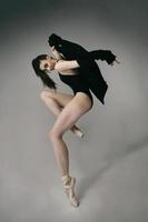 ballerina in a bodysuit and a black jacket improvises classical and modern choreography in a photo studio