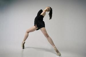 ballerina in a bodysuit and a black jacket improvises classical and modern choreography in a photo studio