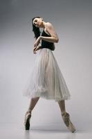 a ballerina in a bodysuit and a white skirt improvises classical and modern choreography in a photo studio