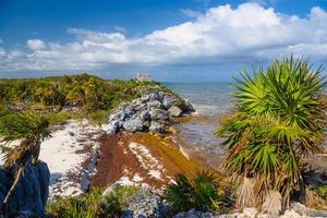 White sand beach with rocks and seaweeds, Mayan Ruins in Tulum, Riviera Maya, Yucatan, Caribbean Sea, Mexico photo