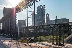 paisaje gris industrial contaminación ambiental residuos de fábrica de cemento. grandes tuberías de la planta de la empresa industrial. montañas de arena y escombros foto