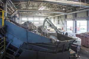 Excavator on primary sorting of garbage at waste processing plant. Separate garbage collection. Recycling and storage of waste for further disposal. photo