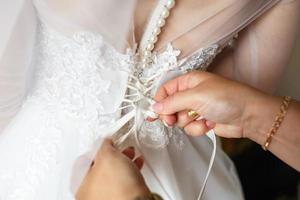 novia joven en vestido de novia está esperando al novio. novia ayuda a sujetar un vestido foto