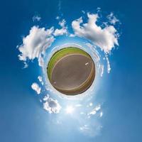 Little planet transformation of spherical panorama 360 degrees. Spherical abstract aerial view in field in nice evening with awesome beautiful clouds. Curvature of space. photo