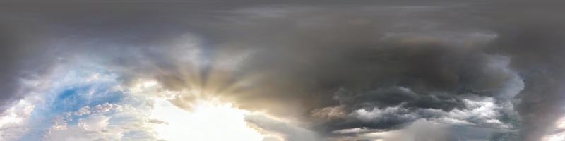 cielo oscuro antes de la tormenta con sol y hermosas nubes negras. vista de ángulo de 360 grados de hdri sin costuras con cenit para usar en gráficos 3d o desarrollo de juegos como cúpula del cielo o editar toma de drones foto