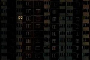 luz en una sola ventana. panorama nocturno plano de luz multicolor en ventanas de edificios de varios pisos. la vida en la gran ciudad foto