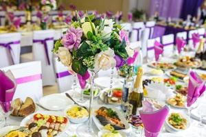 View of the served for decorated wedding dinner table in elite restaurant with beautiful flowers. photo