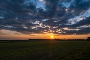 landscape of green field with blue red pink evening sky with beautiful clouds after sunset photo