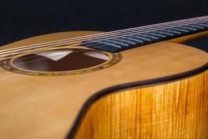 textura de madera de la cubierta inferior de guitarra acústica de seis cuerdas sobre fondo negro. forma de guitarra foto