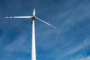 rotating blades of a windmill propeller on blue sky background. Wind power generation. Pure green energy. photo