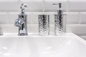 Soap and shampoo dispensers near Ceramic Water tap sink with faucet in expensive loft bathroom photo