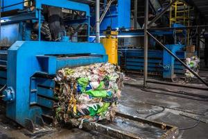 Equipment for pressing debris sorting material to be processed in modern waste recycling plant. garbage press on modern waste recycling processing plant. Business for sorting and processing of waste. photo