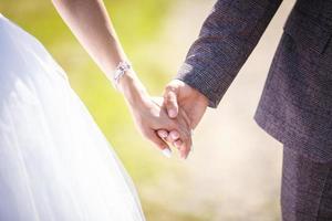 pareja romántica tomados de la mano. amantes o recién casados pareja joven casada en romance. tema de la boda foto