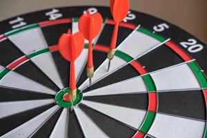 Red dart arrows hitting in the target center of dartboard. Success hitting target aim goal achievement concept photo