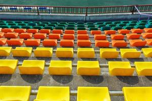 filas multicolores de asientos de plástico en el estadio foto