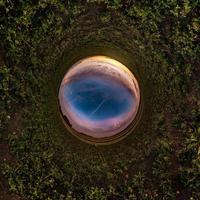 Little planet transformation of spherical panorama 360 degrees. Spherical abstract aerial view in field in nice evening with awesome beautiful clouds. Curvature of space. photo