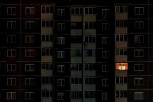 luz en una sola ventana. panorama nocturno plano de luz multicolor en ventanas de edificios de varios pisos. la vida en la gran ciudad foto