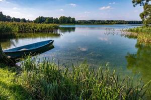 old wooden boat in the reed bushes on the bank of wide river or lake photo