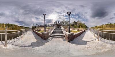 full seamless spherical hdri panorama 360 degrees  angle view on pier of wide river near stairs in sunny summer day and windy weather with beautiful clouds in equirectangular projection, VR content photo