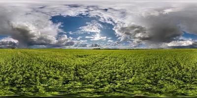 vista de ángulo de 360 grados de panorama hdri esférico completo sin costuras entre campos en primavera con impresionantes nubes antes de tormenta con arco iris en proyección equirectangular, para contenido de realidad virtual vr ar foto