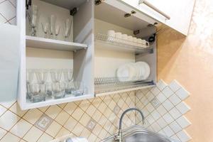 set of plates, cups and wine glasses on the shelf in the kitchen cabinet
