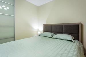Double bed with pillows in interior of the modern intimate bedroom in loft flat in light color style apartments photo
